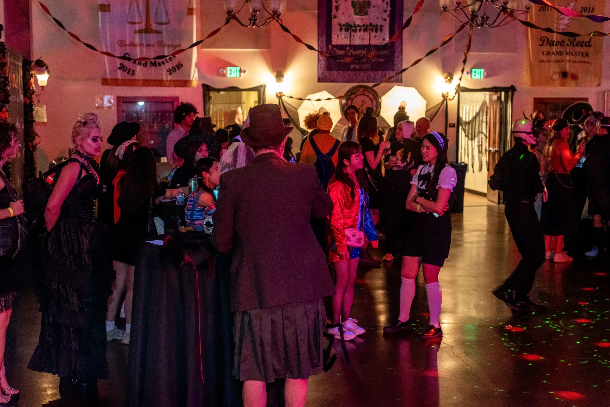 A costumed crowd fills the Zombie Ball dance floor beneath lodge banners and colorful lights.