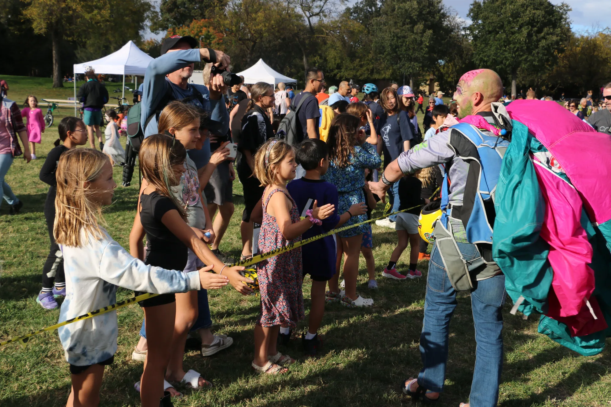 A skydiver greets a girl in the high-five line after landing.